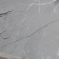 A large piece of slate is resting on a concrete floor.