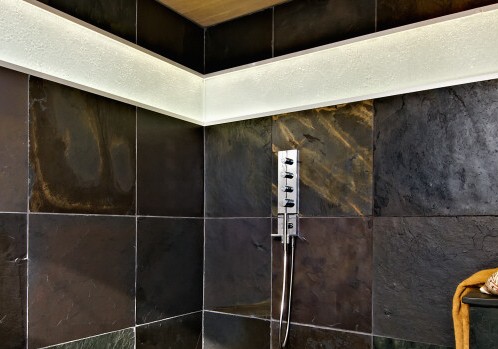 A slate tiled shower with a wooden shower head.