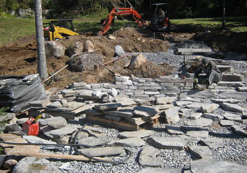 A construction crew is working on a scotia stone patio.