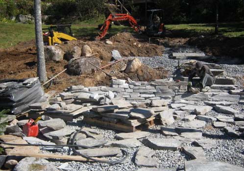 A construction crew is working on a scotia stone patio.