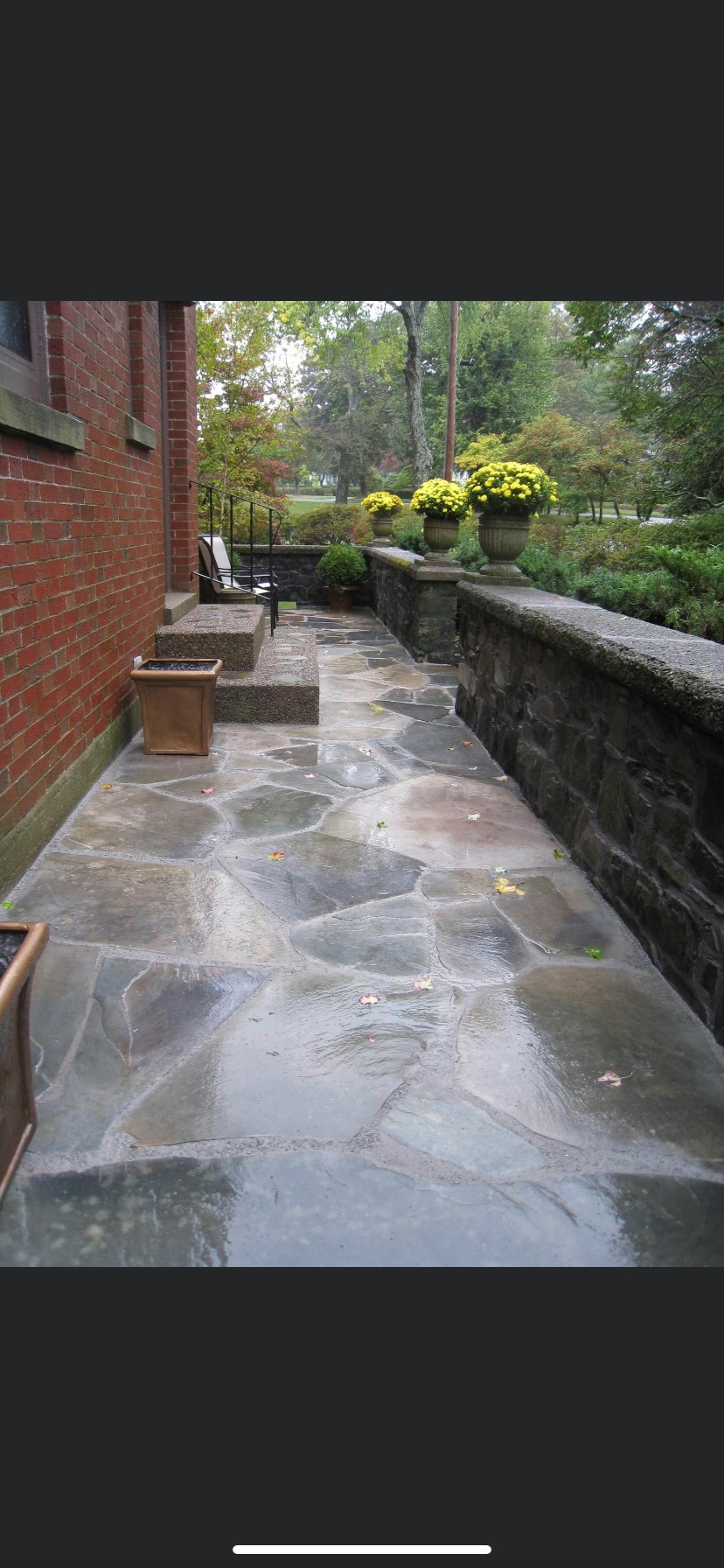 A scotia stone patio with a brick wall in the background.