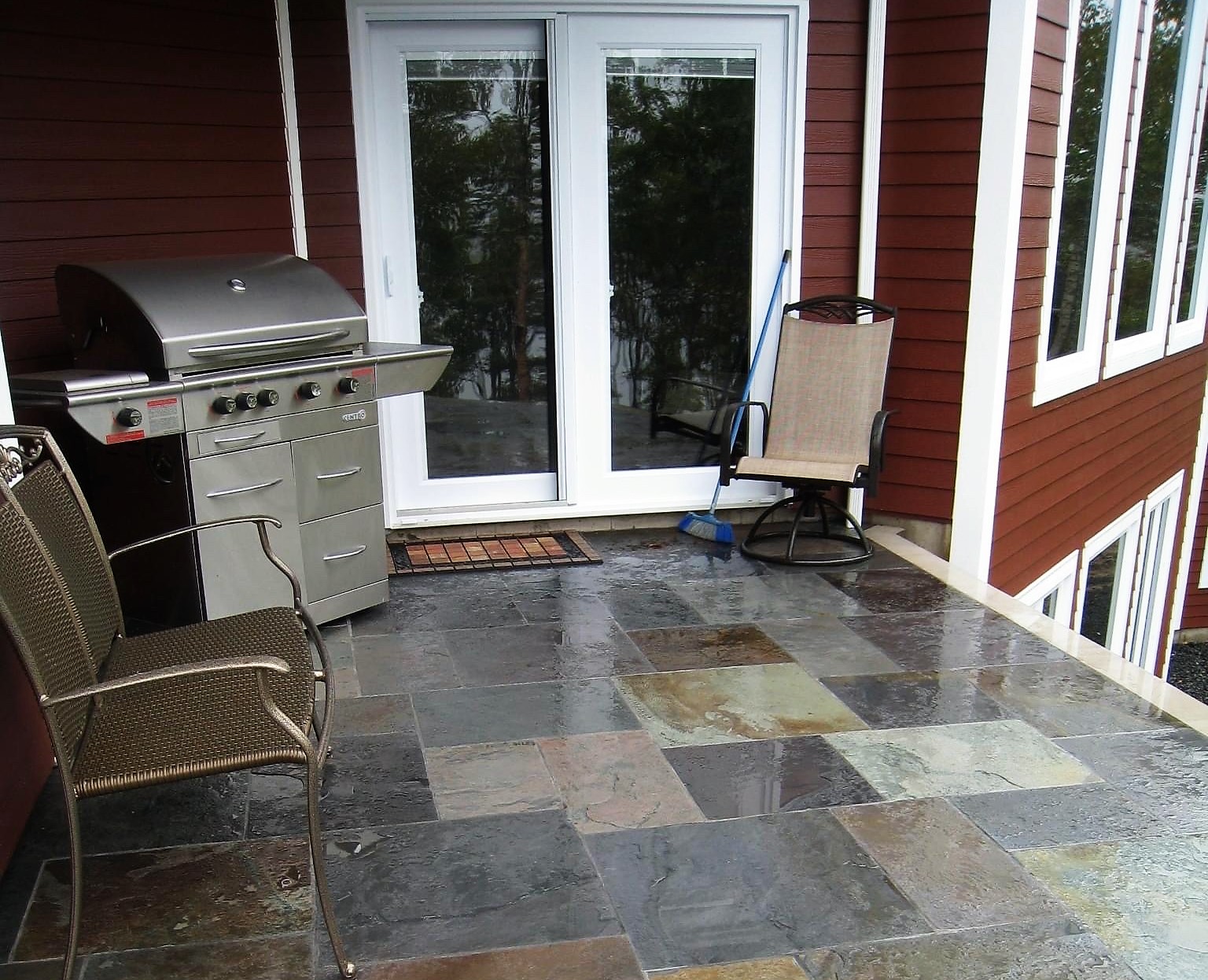 A patio with a scotia stone grill and chairs.